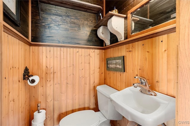 bathroom featuring wood walls, sink, and toilet