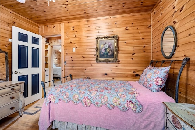 bedroom with light hardwood / wood-style floors, wood walls, and wooden ceiling