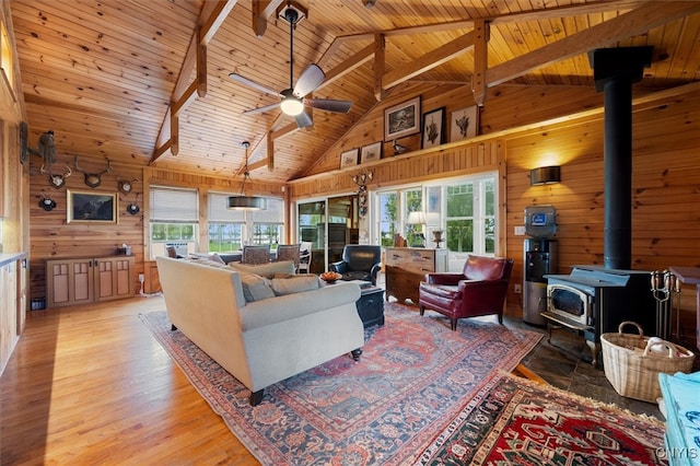 living room with a wood stove, high vaulted ceiling, a healthy amount of sunlight, and wood ceiling