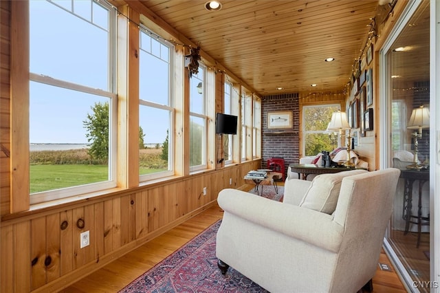 sunroom featuring a wealth of natural light, wooden ceiling, and a water view