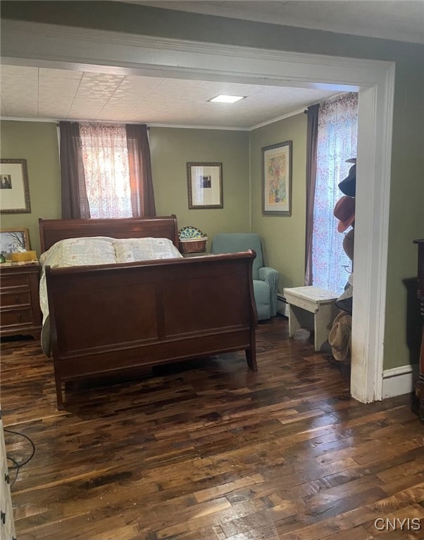 bedroom with ornamental molding and wood finished floors