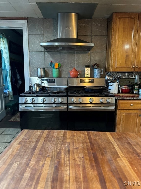 kitchen featuring wall chimney exhaust hood, butcher block countertops, and gas stove