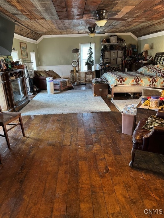 bedroom featuring vaulted ceiling, wainscoting, wood-type flooring, and crown molding