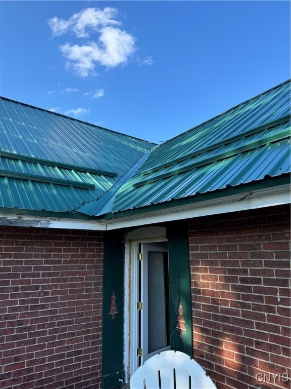 exterior space with metal roof and brick siding