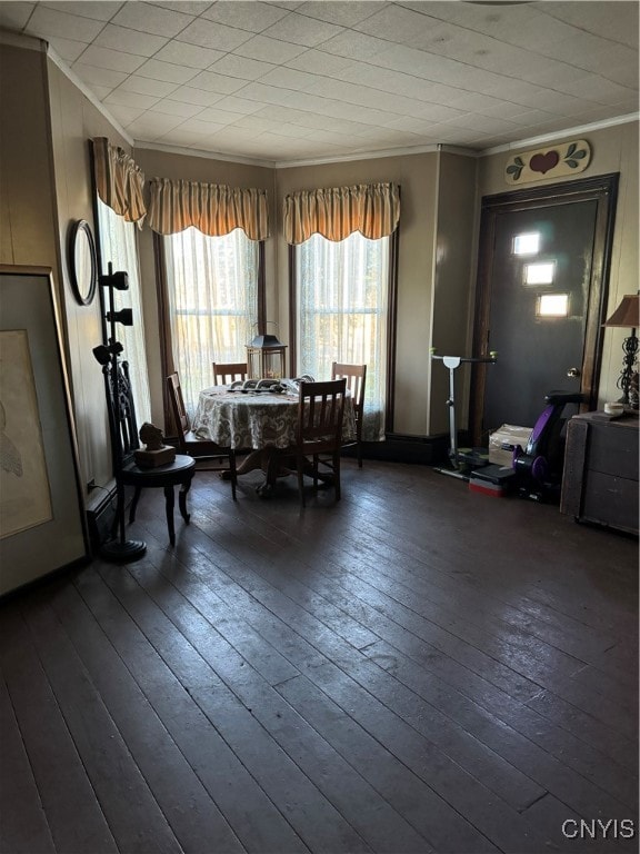 dining space featuring dark wood finished floors and crown molding