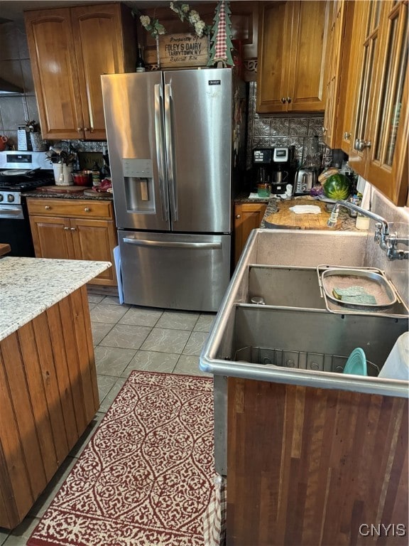 kitchen featuring tasteful backsplash, light tile patterned flooring, stainless steel appliances, and stone countertops