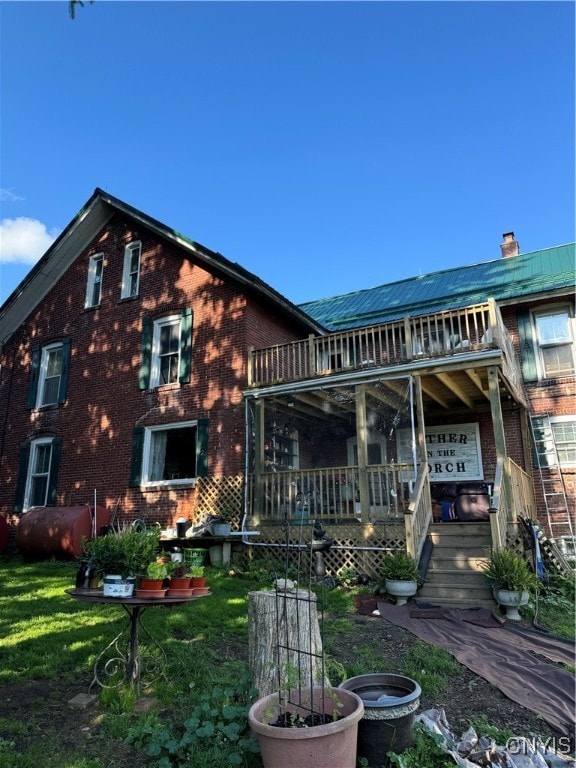 rear view of property with a balcony, heating fuel, a chimney, and a lawn