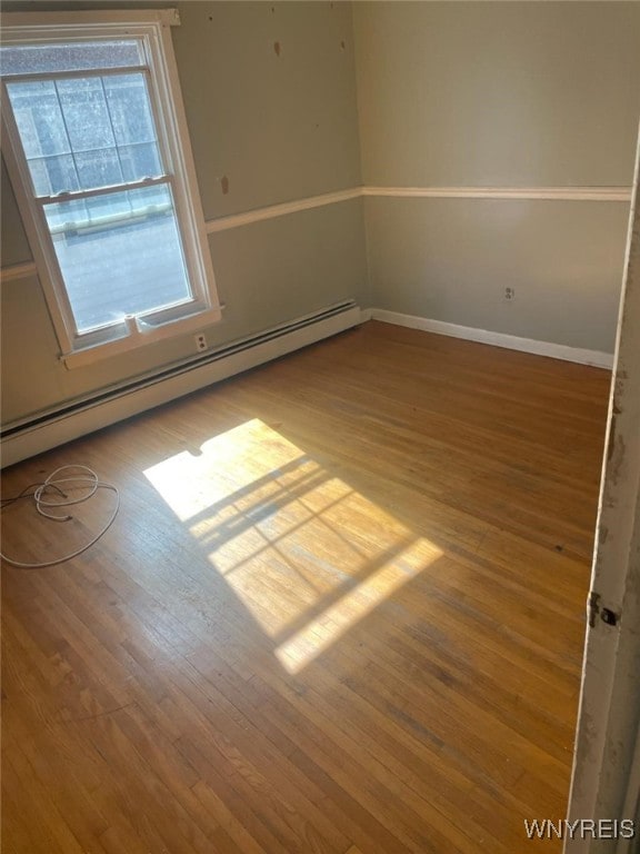 empty room featuring light wood-type flooring and a baseboard heating unit