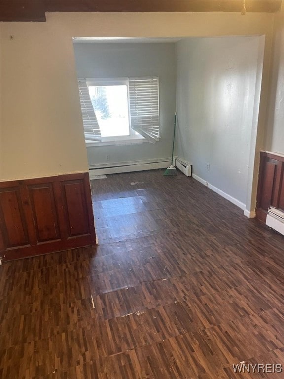 empty room with dark hardwood / wood-style flooring and a baseboard heating unit