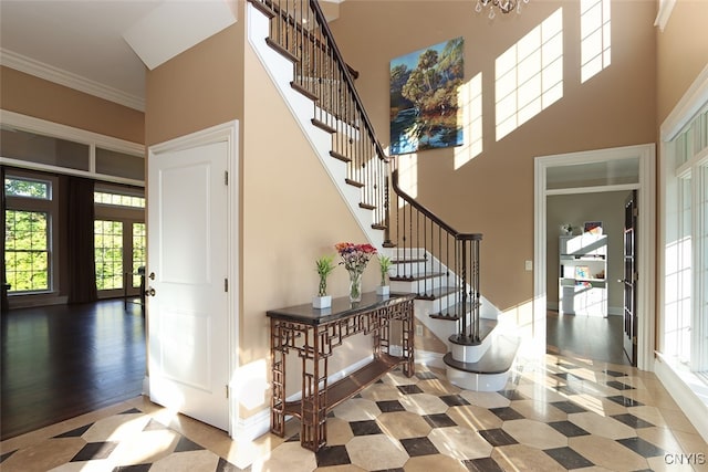 stairway with hardwood / wood-style floors, crown molding, french doors, and a towering ceiling