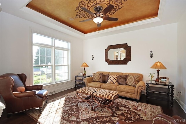 living room featuring dark wood-type flooring, crown molding, a raised ceiling, and ceiling fan