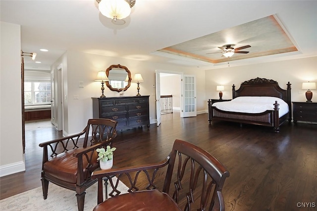 bedroom featuring ceiling fan, a tray ceiling, dark hardwood / wood-style flooring, and french doors