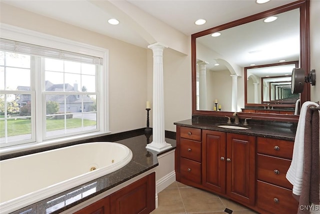 bathroom featuring ornate columns, a tub to relax in, tile patterned floors, and vanity