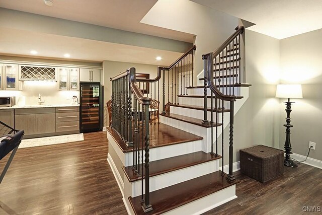 staircase with wet bar, wine cooler, and hardwood / wood-style flooring