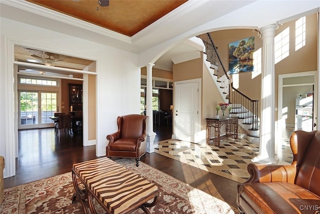 interior space featuring dark wood-type flooring, ornamental molding, ornate columns, and a raised ceiling