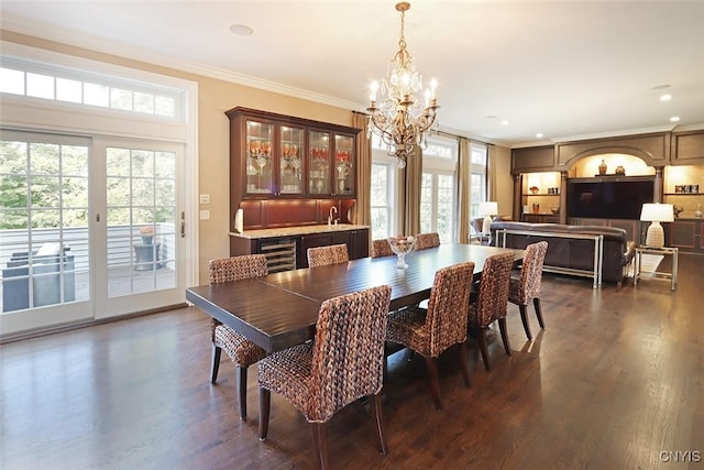 dining area with dark wood-type flooring, ornamental molding, and a notable chandelier