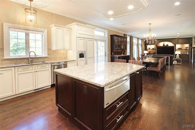 kitchen with dark hardwood / wood-style flooring, stainless steel dishwasher, a kitchen island, and decorative light fixtures