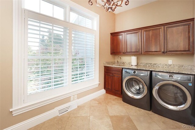 washroom with an inviting chandelier, washing machine and clothes dryer, light tile patterned flooring, cabinets, and sink