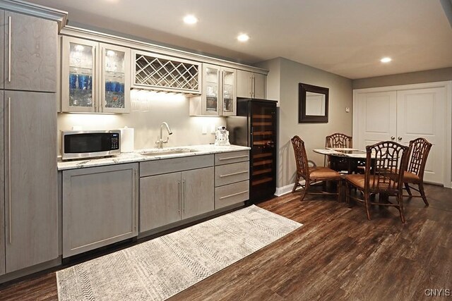 kitchen with wine cooler, sink, dark hardwood / wood-style floors, light stone counters, and gray cabinetry