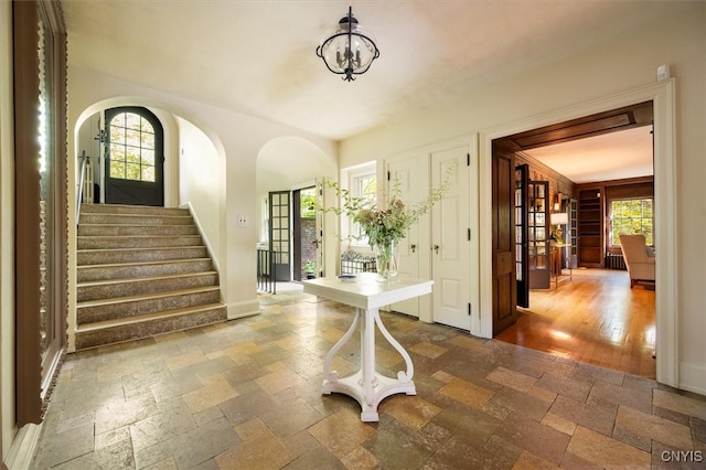 foyer entrance with french doors, a wealth of natural light, and hardwood / wood-style floors