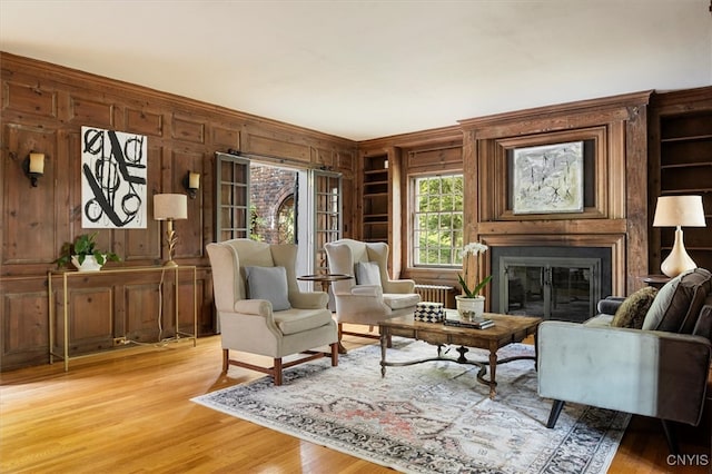 living area featuring built in shelves, light hardwood / wood-style floors, and wood walls