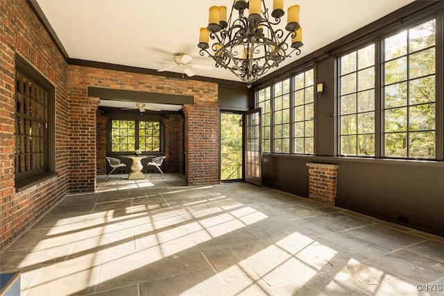 empty room featuring brick wall, ornamental molding, and ceiling fan with notable chandelier