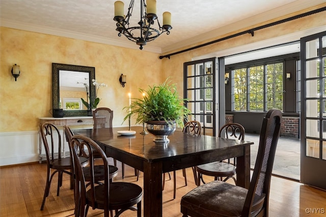 dining space featuring light hardwood / wood-style floors, ornamental molding, and an inviting chandelier