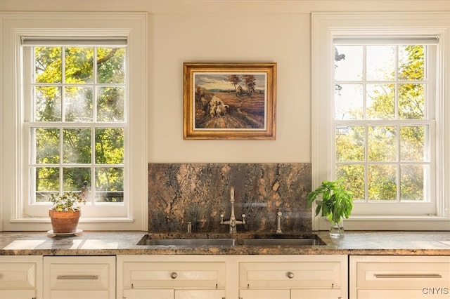 bar with sink, white cabinetry, decorative backsplash, and plenty of natural light