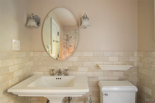 bathroom with tile walls, toilet, and a sink
