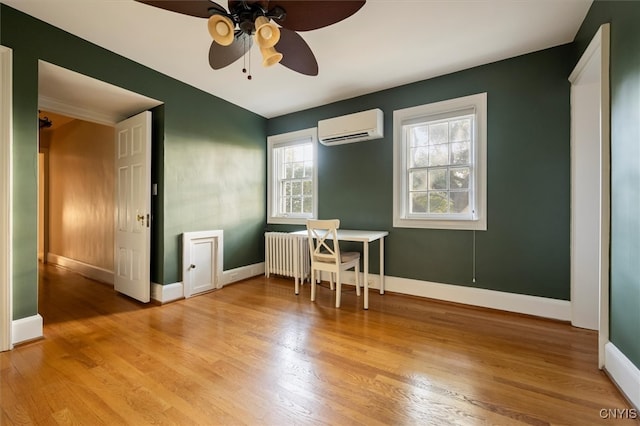 unfurnished dining area with an AC wall unit, radiator, light hardwood / wood-style floors, and ceiling fan