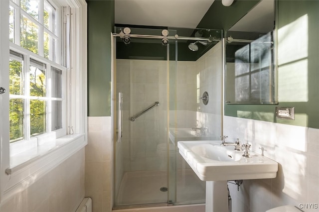 bathroom featuring a shower with door, toilet, and tile walls