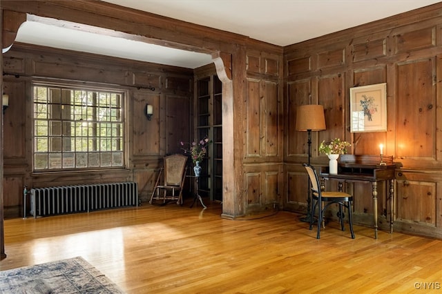 interior space with wood walls, radiator, and light wood-type flooring