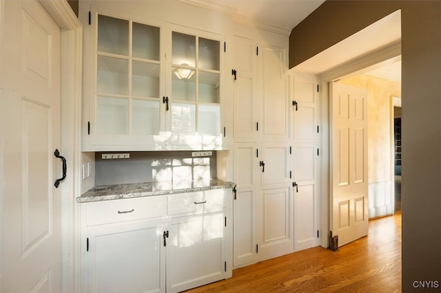 bar featuring light hardwood / wood-style floors, white cabinets, and light stone counters