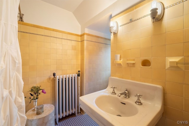 bathroom featuring lofted ceiling, radiator heating unit, tile walls, sink, and tile patterned flooring