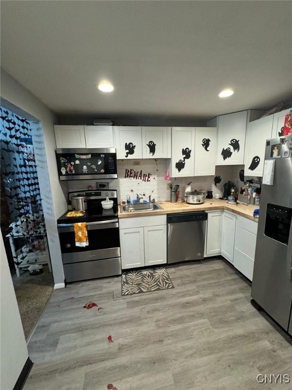 kitchen with stainless steel appliances, light hardwood / wood-style floors, sink, and white cabinetry