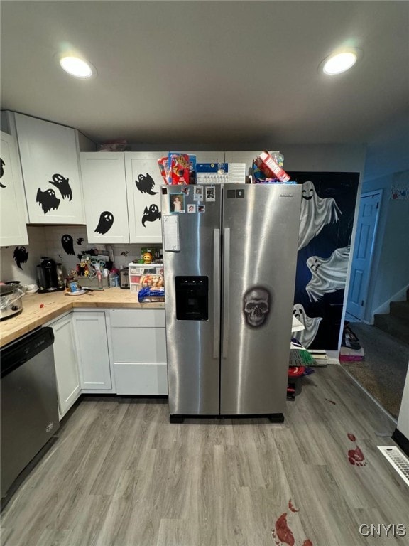 kitchen featuring white cabinets, appliances with stainless steel finishes, light hardwood / wood-style floors, and butcher block countertops