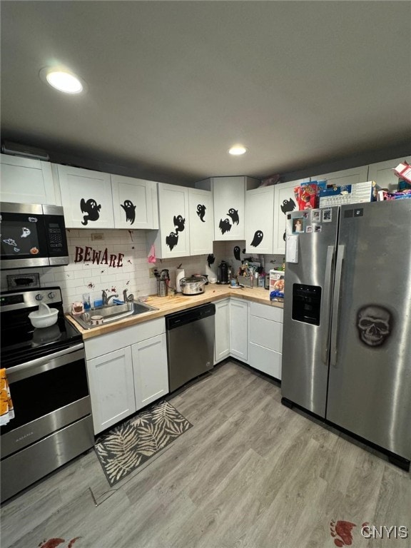 kitchen with light hardwood / wood-style floors, stainless steel appliances, sink, and white cabinetry