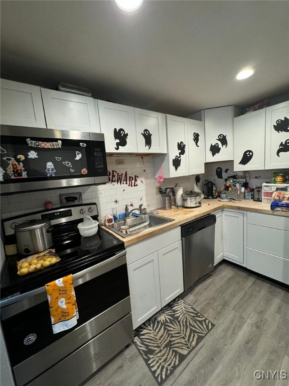 kitchen featuring decorative backsplash, stainless steel appliances, sink, light hardwood / wood-style floors, and white cabinetry