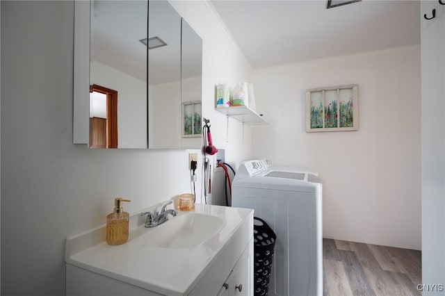 laundry area featuring ornamental molding, sink, light hardwood / wood-style flooring, cabinets, and washer and dryer