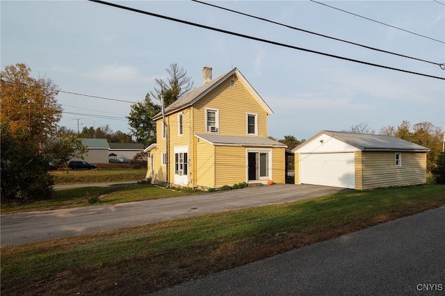 view of property featuring a front lawn, a garage, and an outdoor structure