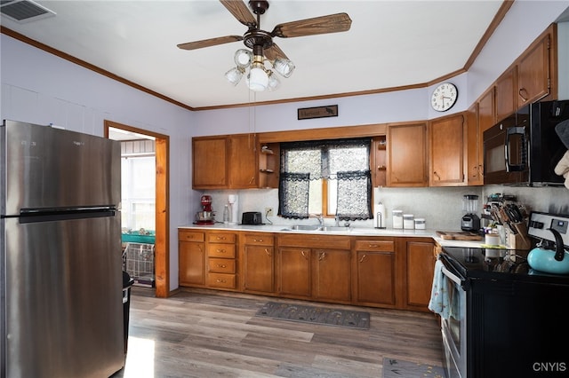 kitchen featuring light wood-type flooring, stainless steel refrigerator, sink, electric stove, and ornamental molding