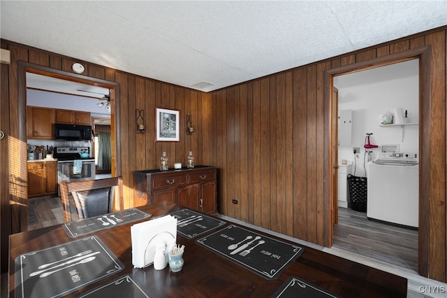 interior space with wooden walls, hardwood / wood-style floors, tasteful backsplash, and stainless steel range oven