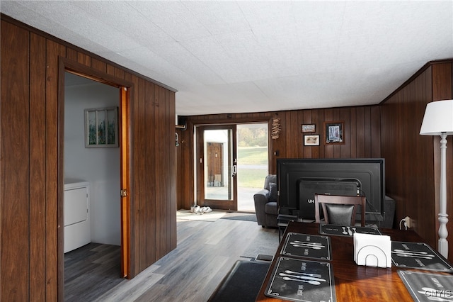 interior space featuring dark wood-type flooring, a textured ceiling, wooden walls, and washer / dryer