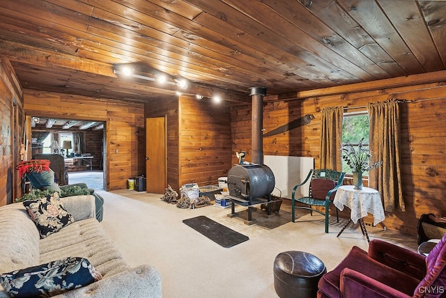 living area with wooden walls, a wood stove, and wood ceiling