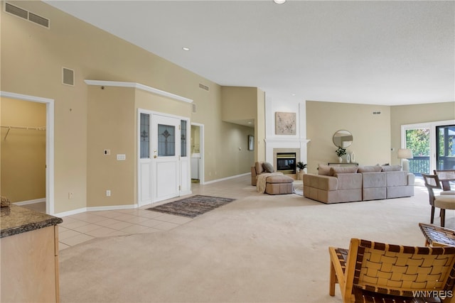 living room with a fireplace, a towering ceiling, and light colored carpet