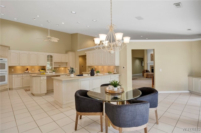 tiled dining space with ceiling fan with notable chandelier, crown molding, and a towering ceiling