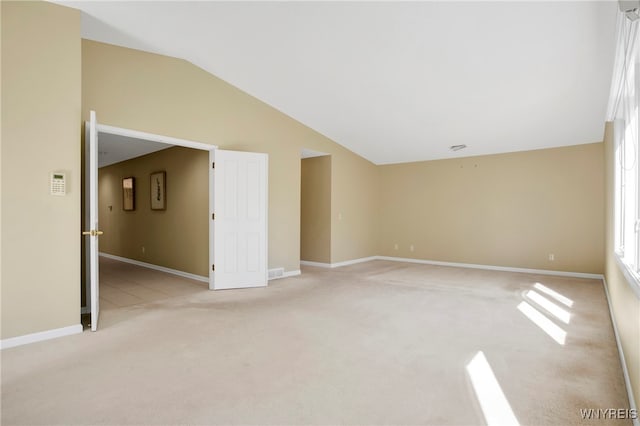 spare room with light colored carpet and lofted ceiling