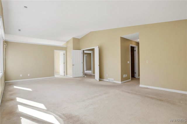 carpeted empty room featuring vaulted ceiling