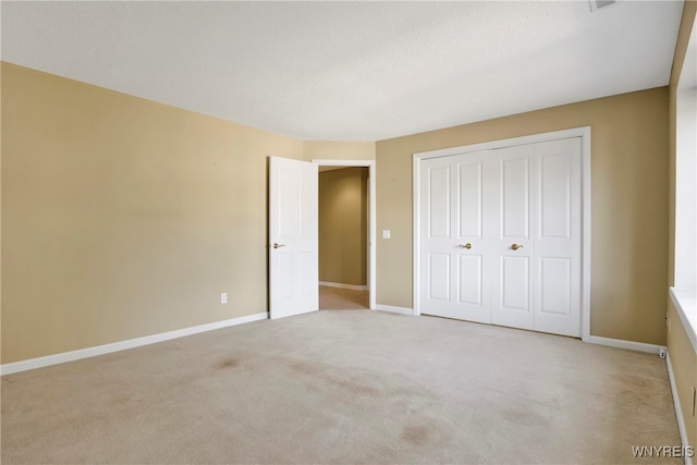 unfurnished bedroom featuring a closet, light colored carpet, and a textured ceiling