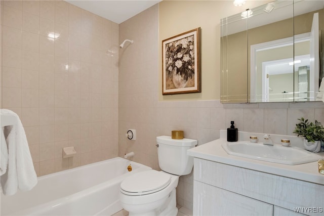 full bathroom with tile walls, tiled shower / bath combo, vanity, and toilet